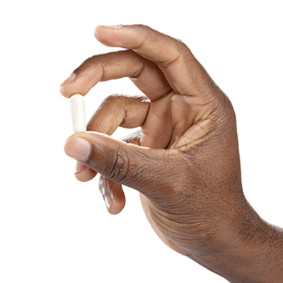 Single off-white Vital Vitamins Multi Collagen Complex capsule held between finger and thumb against a black background